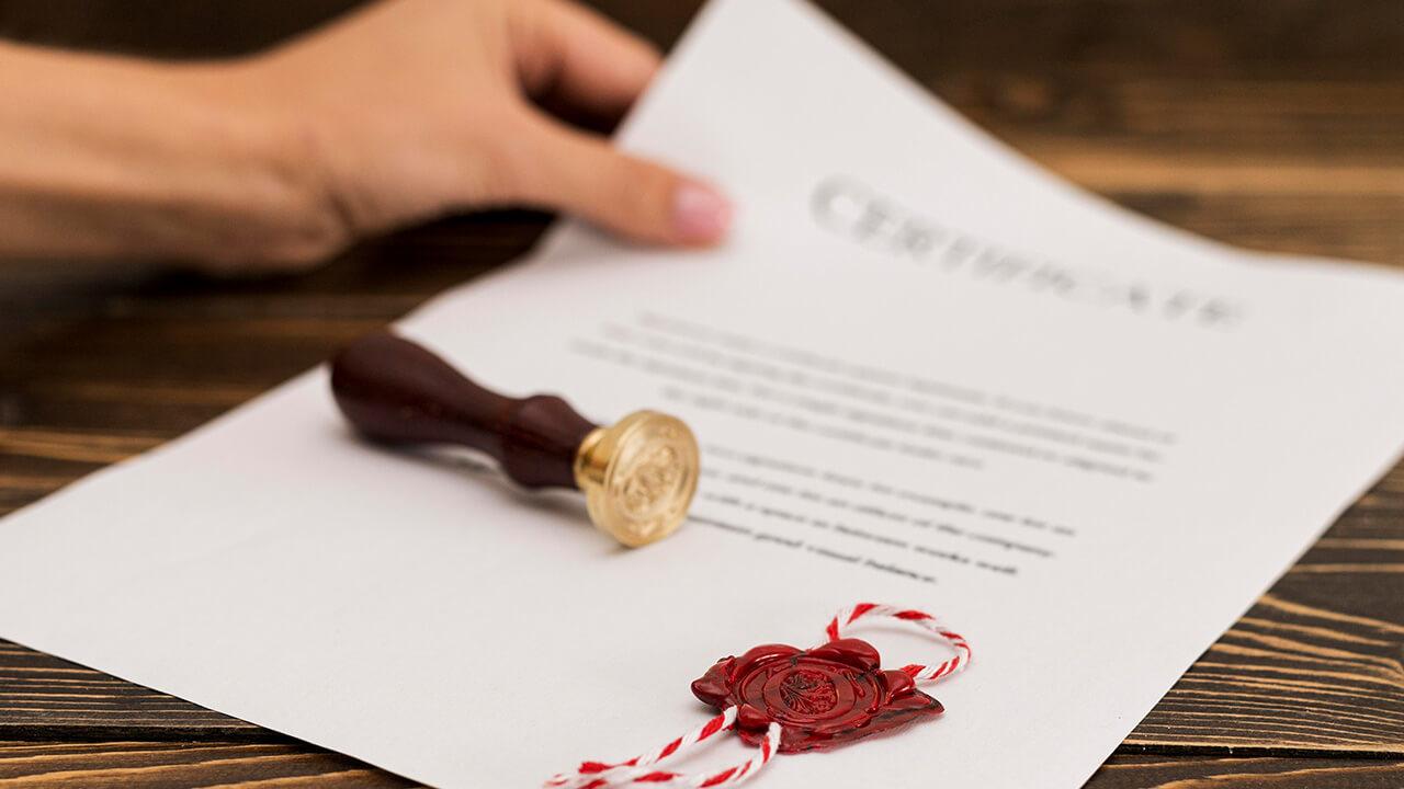 Mão segurando um certificado com uma carimbo em cima.