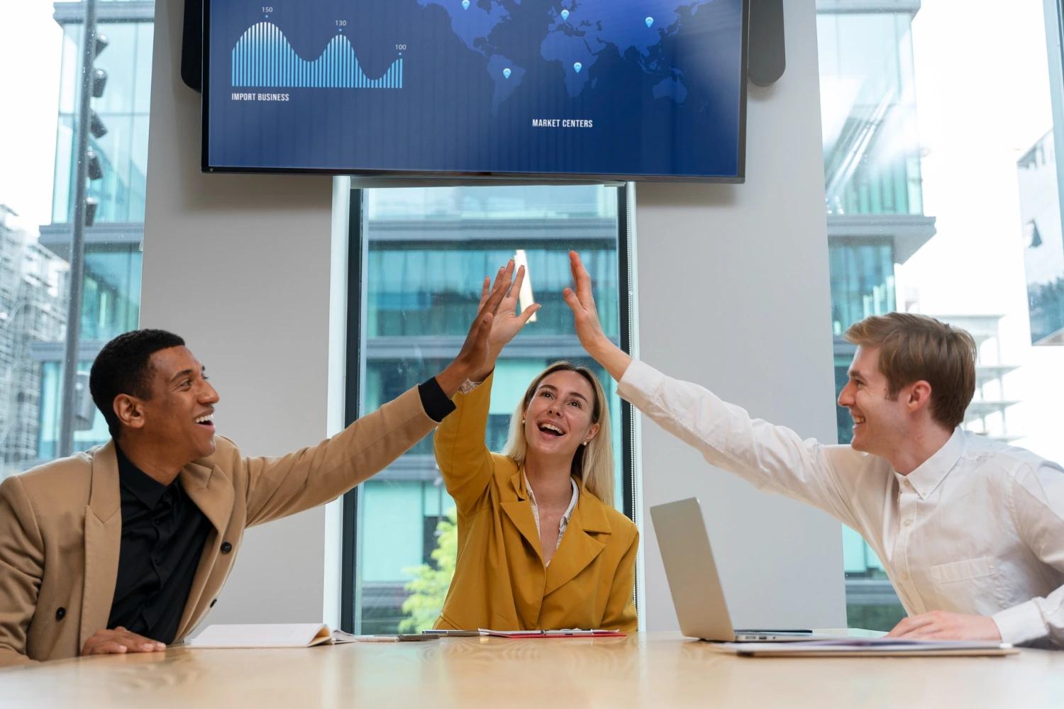 Cena corporativa mostrando três profissionais sorrindo e comemorando com um high-five durante uma reunião, simbolizando colaboração, agilidade e liderança adaptativa 4.0 em um ambiente moderno de negócios.