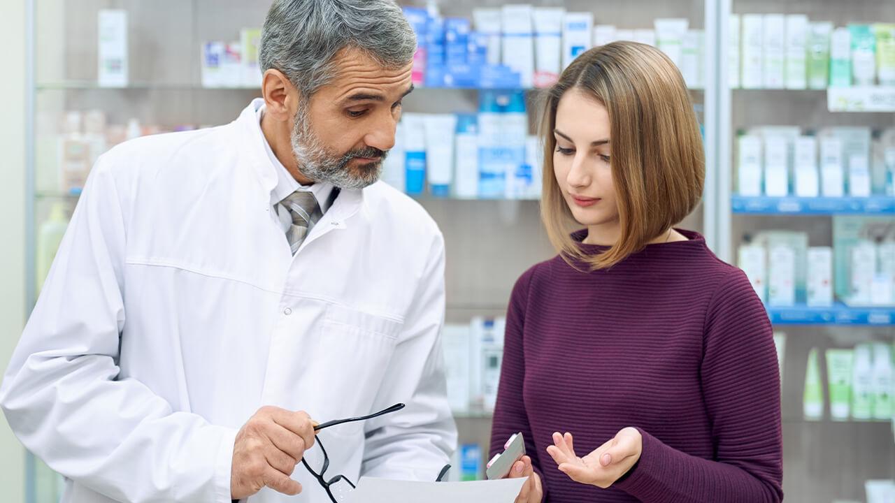 Auxiliar de farmácia ajudando mulher.